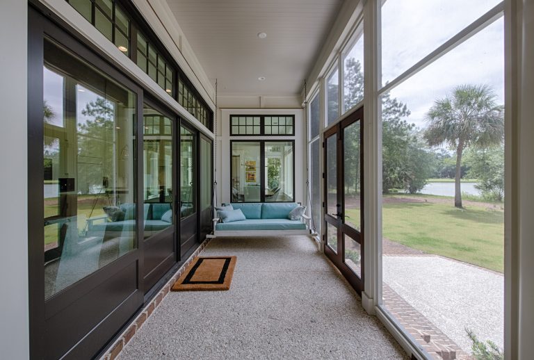 Screened back porch with bed swing, tabby floor, and 12-ft sliding doors that open to the living room.
