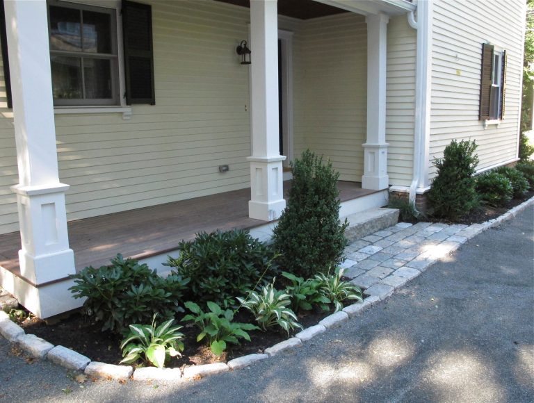 Shade tolerate plants and a crisp cobblestone border and landing mark the side entrance