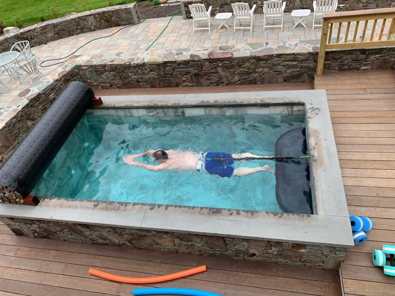 Soake Pool in a private backyard setting. Interesting and beautiful mix of materials and texture was used on wood deck and stone surround. Customer can swim in place with Swim Tether system. by Soake Pools | Pool design | Pool Contracting | Swimming Pool Ideas | Swimming Pool Design Ideas