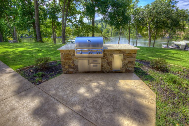 Stain and texture concrete patio with built-in grill and stone table top for food prep and serving.
