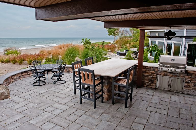 Stone patio installation with an outdoor bar and outdoor grill.