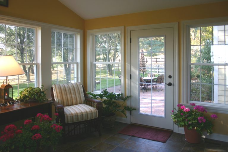 Sun porch attached to the back of the house with tile flooring and windows on all walls for natural light