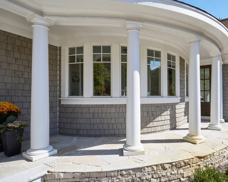 The curved wall of the turret is clad in white cedar shake stained gray. White columns and a matching white bead board ceiling add to the Nantucket feel. Photo by Mike Kaskel by Orren Pickell Building Group | Outdoor Photos | Porch | Landscaping | Landscape Design | Outdoor Living Space | Porch Design Ideas | Outdoor Living Space Ideas | Backyard Design