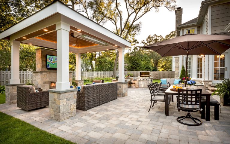 The custom-built pavilion features nine-foot tall openings and painted architectural columns mounted on stone masonry piers. Its design and placement maintain open views of the yard from inside the house.