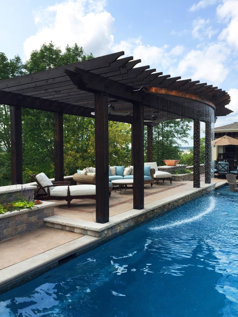 The custom pergola and rain curtain feature attract pool users young and old. The carpentry work, plumbing and hardscapes all complement each other perfectly and were coordinated flawlessly.