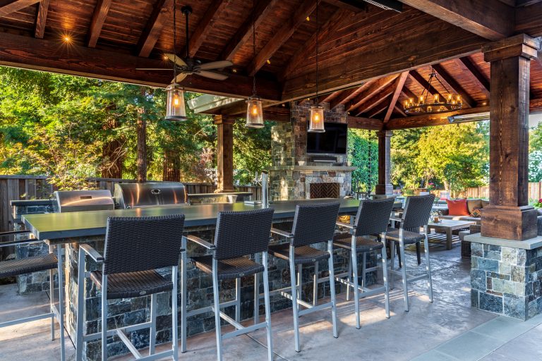 The outdoor kitchen is equipped with a ceiling fan and pendant lights to ensure that practicality also accompanies style.