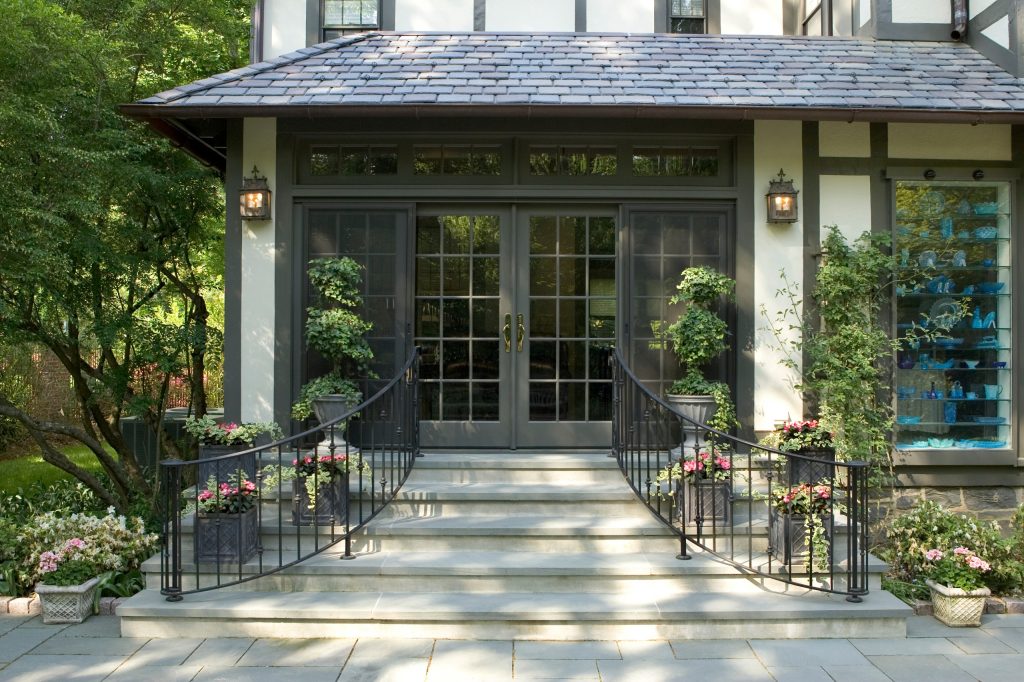 The outdoor patio was enclosed and the custom rod iron curved staircase/railings were added tying the extensive gardens to the home.
