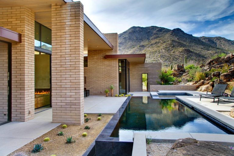 The pool is protected and shaded by the rocky hillside and the house itself, but open to the dome of the desert sky. William Lesch Photography