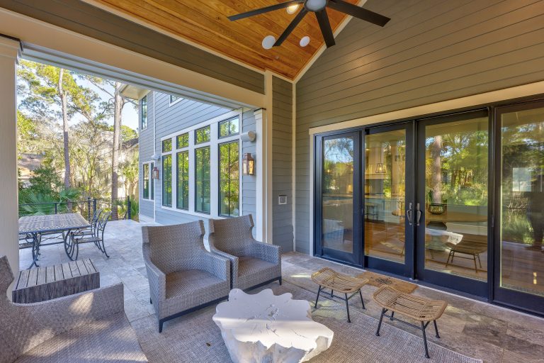 The rear covered porch with a brick fireplace, grill, and refrigerator. Your right; supply chain issues = no cushions