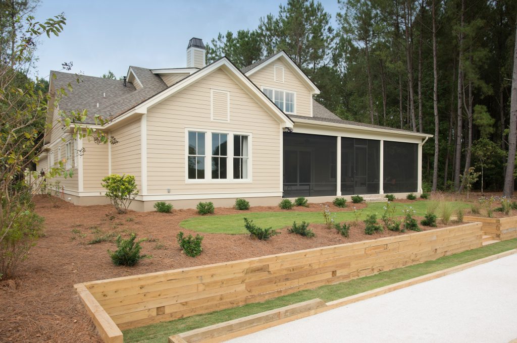 The rear exterior of the Palmetto showcases the large screened in porch and pretty Master bedroom window that over looks the bocci court and landscaped backyard. by Shoreline Construction and Development | Outdoor Photos | Porch | Landscaping | Landscape Design | Outdoor Living Space | Porch Design Ideas | Outdoor Living Space Ideas | Backyard Design