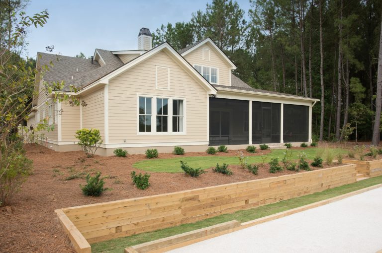 The rear exterior of the Palmetto showcases the large screened in porch and pretty Master bedroom window that over looks the bocci court and landscaped backyard. by Shoreline Construction and Development | Outdoor Photos | Porch | Landscaping | Landscape Design | Outdoor Living Space | Porch Design Ideas | Outdoor Living Space Ideas | Backyard Design