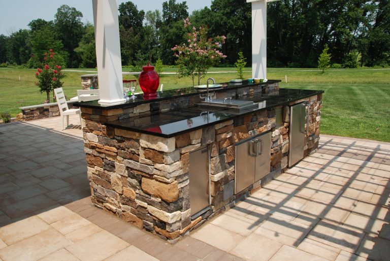 The stone veneer and granite excellently conceal the more practical parts responsible for bringing the utilities out to this kitchen. The pergola provides shade right where it is needed.