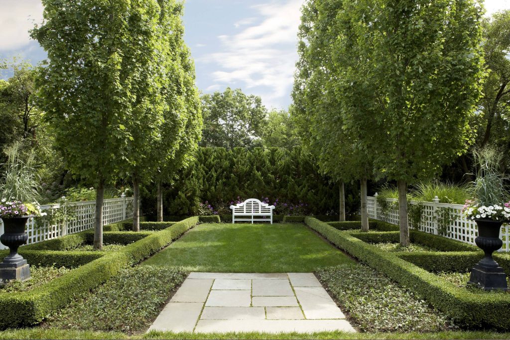 The trees and shrubs create a focal point and path to an elegant white bench.

Photo by Tony Soluri Photo of a large traditional full sun backyard stone formal garden in Chicago for summer. by Scott Byron & Co., Inc. | Backyard Design | Outdoor Living Spaces | Landscape Design | Backyard Ideas | Landscaping | Landscaping Ideas | Landscape Installation