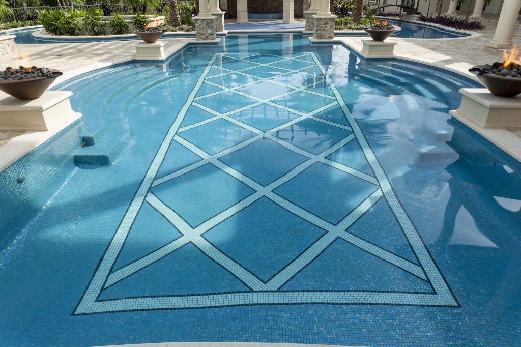 The uniquely shaped swimming pool is completely dressed in hand cut glass tile from Mexico including decorative in-pool detailing. Tiling by Mosaicist.