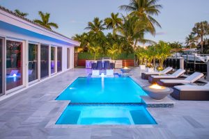 This custom pool & spa in Pompano Beach is the perfect outdoor setting for tranquility and peace. With beautiful custom made fire and water bowls by Van Kirk & Sons Pools & Spas, sunshelf for lounging, and custom decking, this backyard is ready for fun!