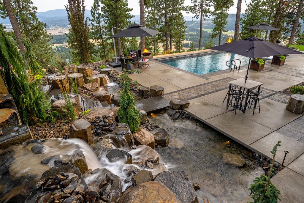 This expansive project includes a custom fire pit with a gorgeous view of Newman Lake, a large pool, and a massive boulder water feature overlooking the entertainment space.