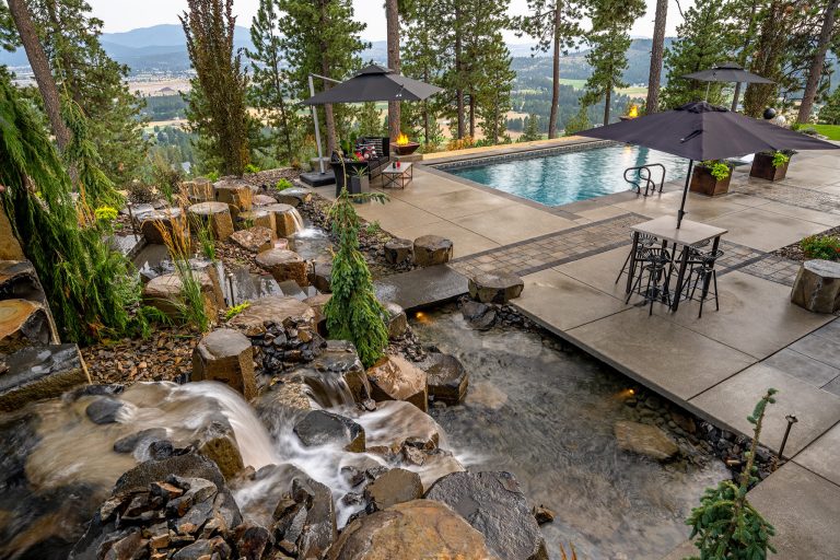 This expansive project includes a custom fire pit with a gorgeous view of Newman Lake, a large pool, and a massive boulder water feature overlooking the entertainment space.