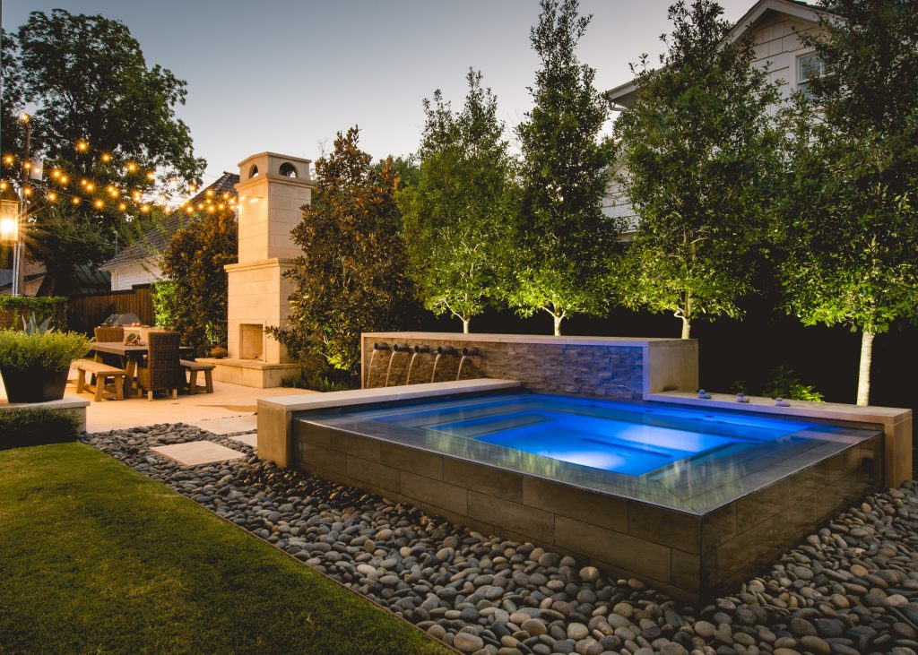 This infinity edge spa with water feature is designed to be a visual work of art. The wall has custom Bobe water scuppers, is veneered with ledgestone and a lueders limestone cap and ends.