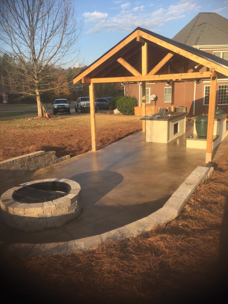 This is a smooth-cut cedar pergola with scored and stained concrete floor and fire pit kit