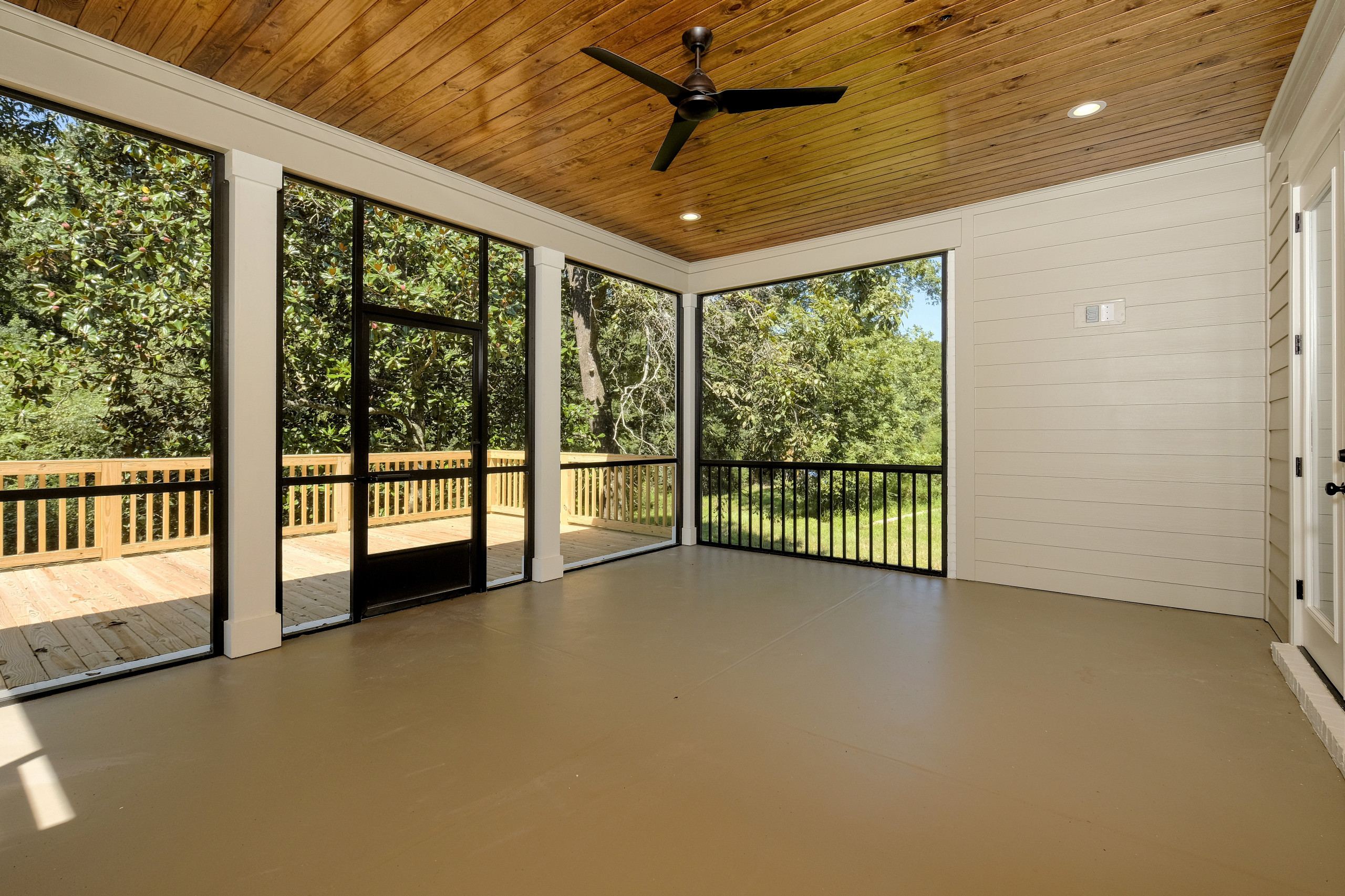 This is an example of a large craftsman screened-in back porch design in New Orleans with a roof extension.