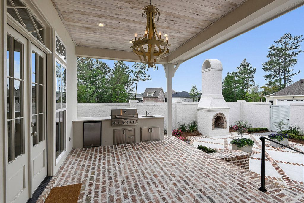 This is an example of a large transitional brick porch design in New Orleans with a roof extension.