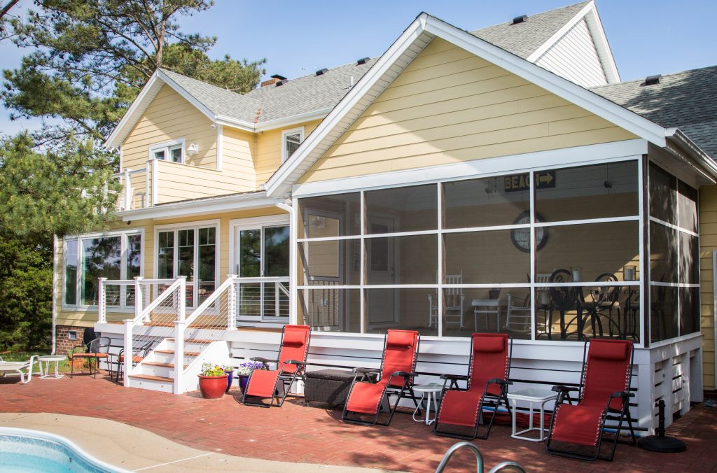 This is an example of a mid-sized coastal brick screened-in back porch design in Other with a roof extension. by J.M. Froehler Construction | Outdoor Photos | Porch | Landscaping | Landscape Design | Outdoor Living Space | Porch Design Ideas | Outdoor Living Space Ideas | Backyard Design