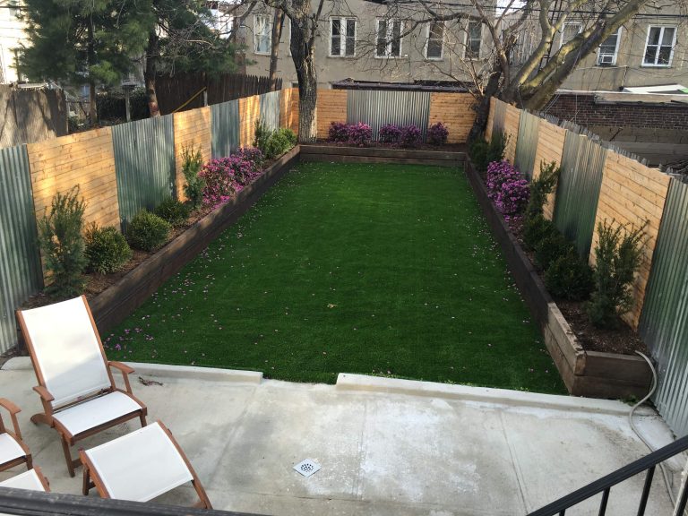 This is an example of a mid-sized contemporary full sun backyard concrete paver landscaping in New York.