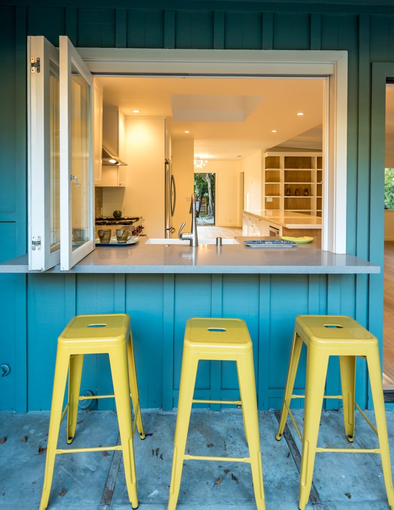 This is the view from outside the kitchen area of this home we remodeled. We installed a bifold window and continued the countertop through the window creating a bar on the other side.