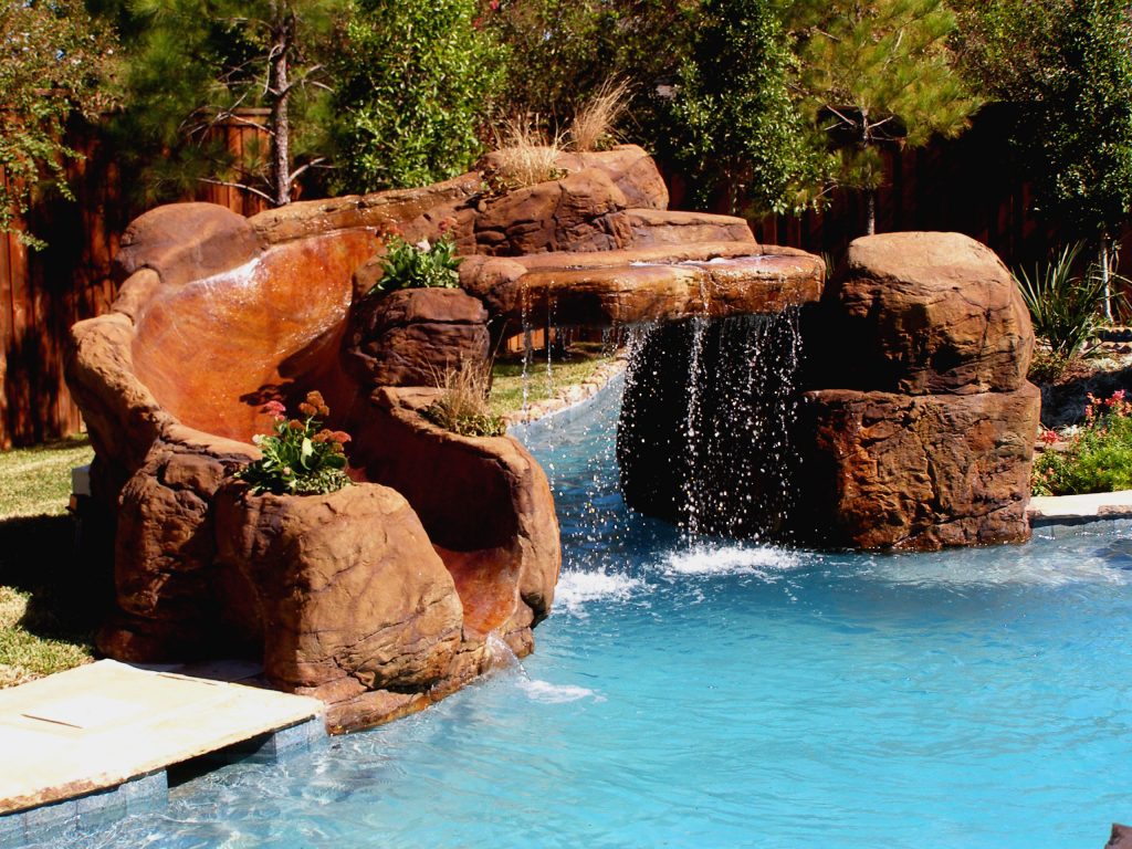 This natural pool features a lazy river and its own island. The bridge gives access to the gazebo, grilling station and slide. The river enters the pool through a cave and waterfall.
