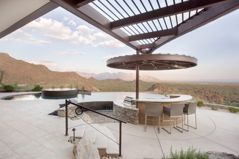 This patio was designed for the ultimate entertainment experience with an outdoor kitchen and a negative edge pool with a swim-up bar. Photo by Robinette Architects, Inc.