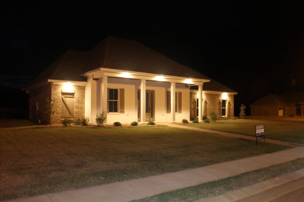 This photo highlights the painted brick and square columns on the front porch. Eave lighting adds a warm touch.