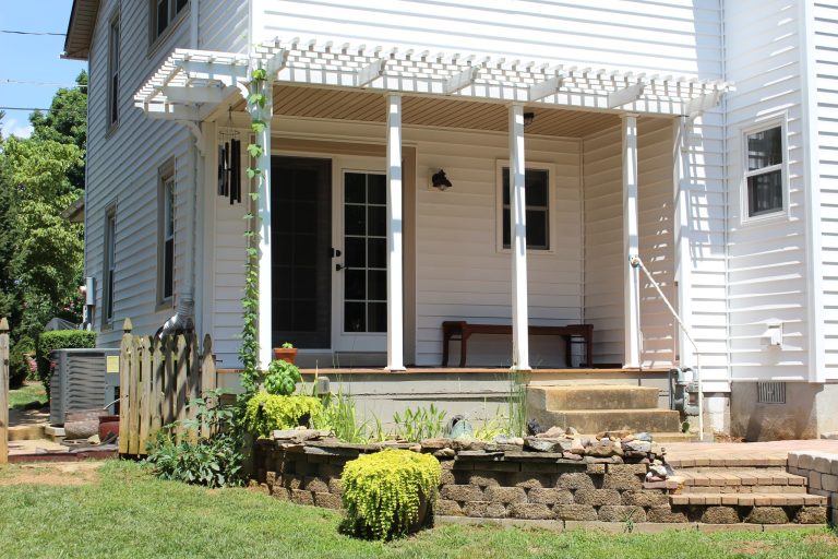 This porch with a pergola extension overlooks a small patio and koi pond. The stairs lead down to the backyard.