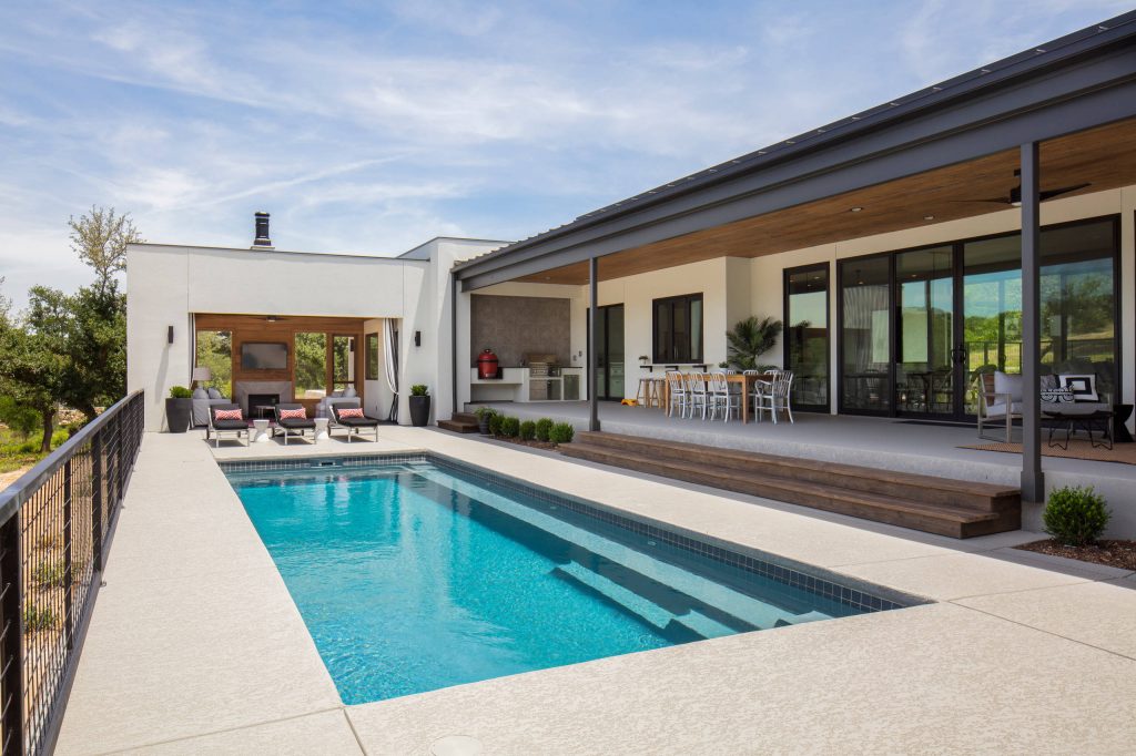 This steel and wood covered patio makes for a great outdoor living and dining area overlooking the pool There is also a pool cabana with a fireplace and a TV for lounging poolside. by Olson Defendorf Custom Homes | Pool design | Pool Contracting | Swimming Pool Ideas | Swimming Pool Design Ideas
