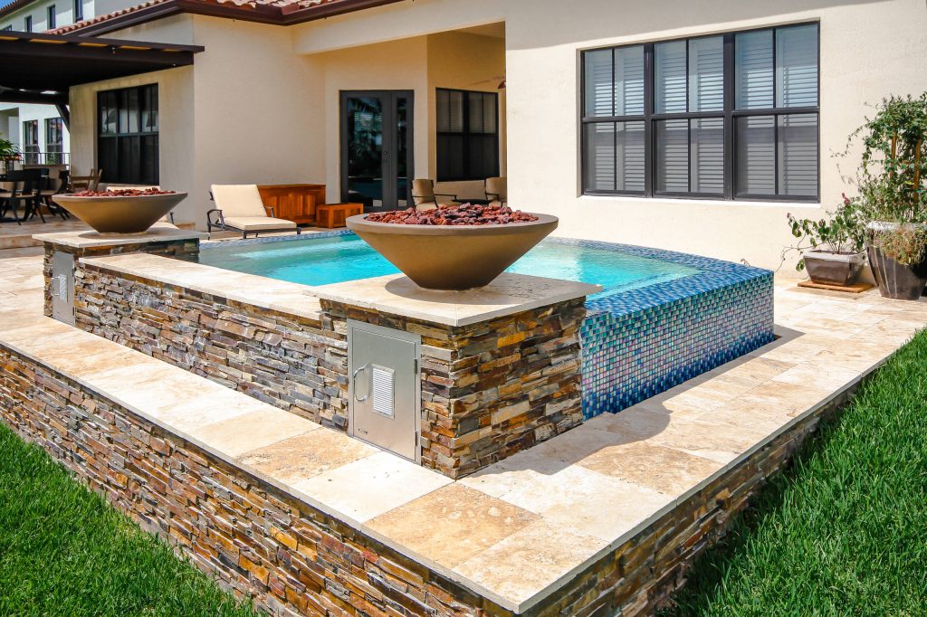 This swim spa with custom fire bowls and outdoor kitchen in Cooper City provides the perfect relaxing atmosphere.