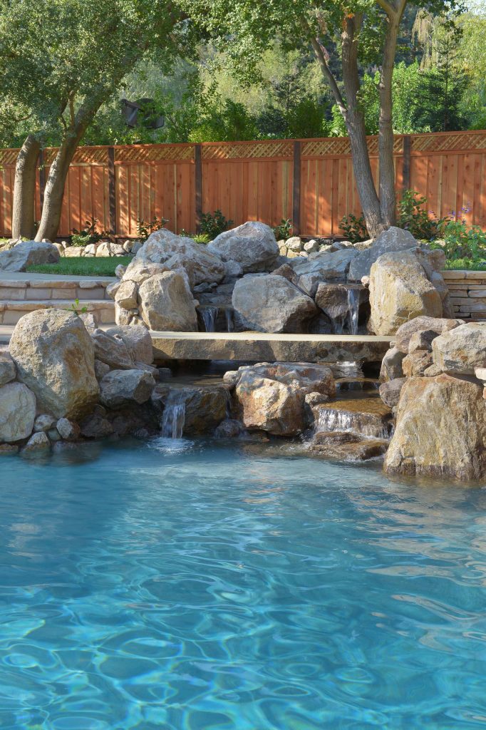 This water fall is complete with a slab cut stone foot bridge. We even installed a LED light under the bridge so the light glows out from the water under the bridge. This pool has a Paramount PCC-2000 in-floor cleaner throughout the pool interior and ledges