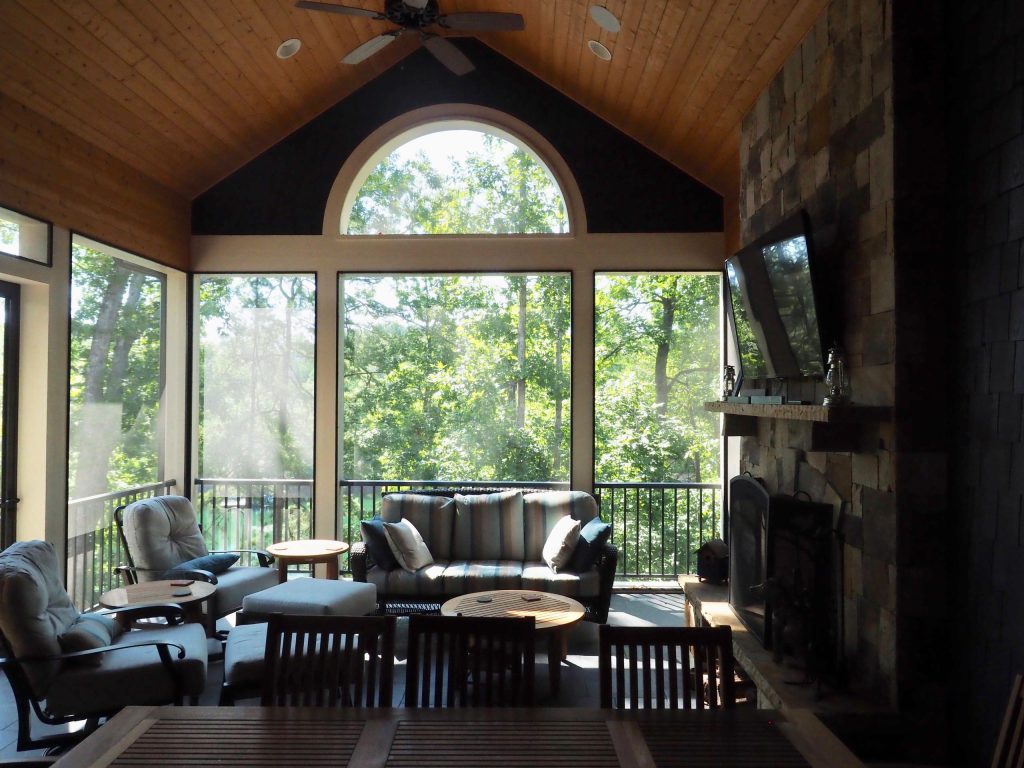 Three seasons room, covered porch, with TV above fireplace mantle and whole home audio speakers int the ceiling.