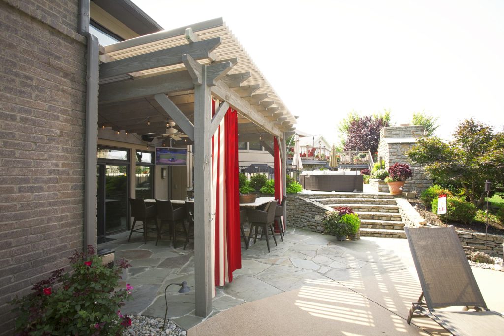 Timber framed attached pergola with the dovetail mortise and tenon joint system with fan and privacy curtains. Louvered roof opens and shuts for implement weather.