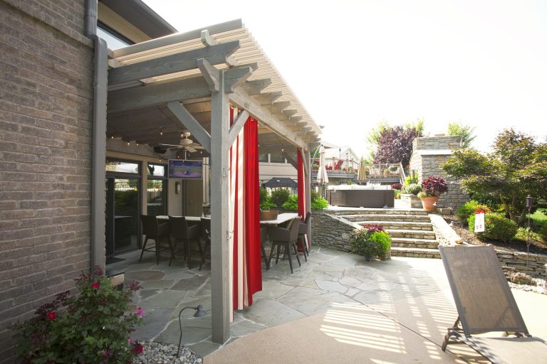 Timber framed attached pergola with the dovetail mortise and tenon joint system with fan and privacy curtains. Louvered roof opens and shuts for implement weather.