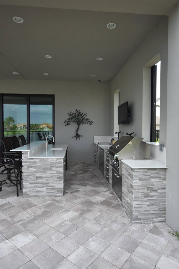 Trendy backyard concrete paver patio kitchen photo in Miami with a roof extension