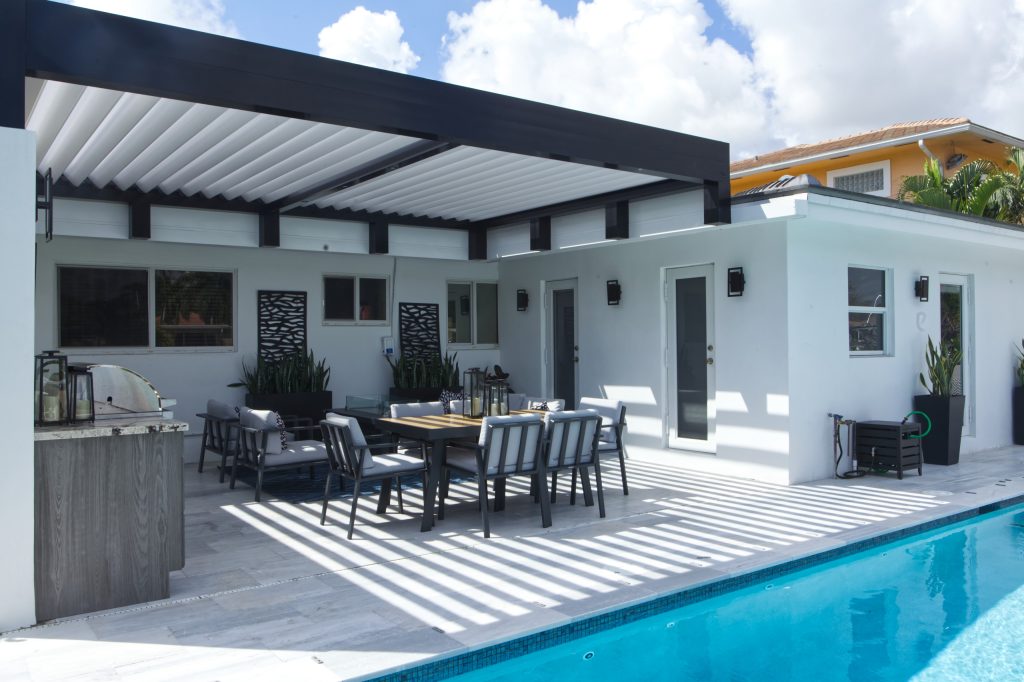 Trendy backyard stone patio kitchen photo in Miami with a pergola