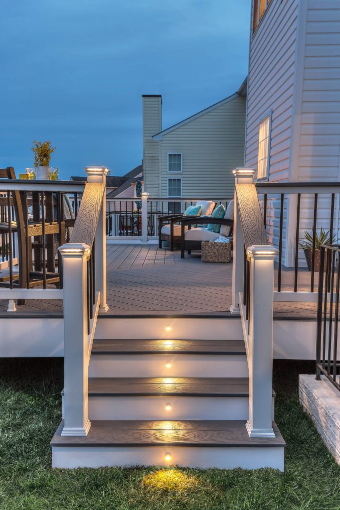 Trex Select railing in Classic White and Pebble Grey cocktail rail. This deck also features Square LED Post Cap Lights and Stair Riser Lights from the Trex Deck Lighting collection.