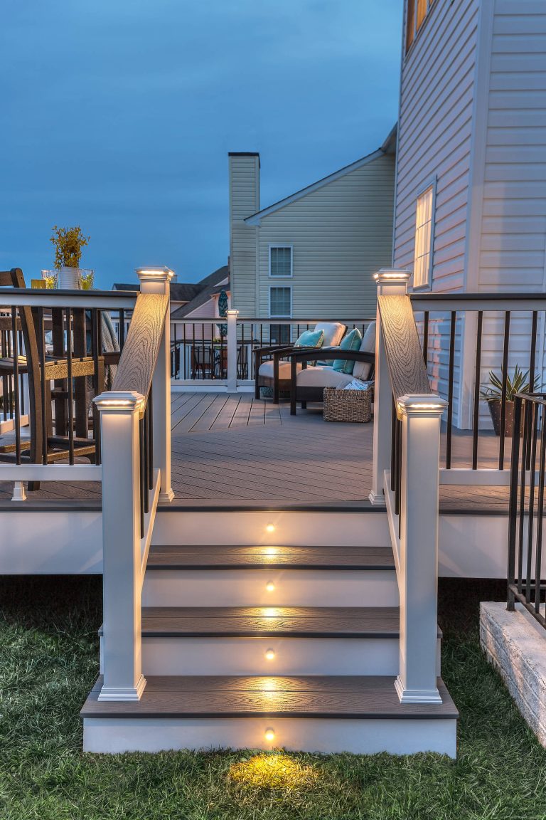 Trex Select railing in Classic White and Pebble Grey cocktail rail. This deck also features Square LED Post Cap Lights and Stair Riser Lights from the Trex Deck Lighting collection.