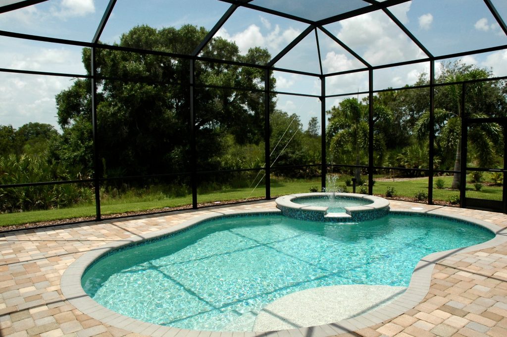 Tropical Backyard Pool, free form shape with hot tub and fountain. Pool is textured pebble finish with glass tiles, sun deck and steps. Deck is concrete pavers. by Well Dressed Homes | Pool design | Pool Contracting | Swimming Pool Ideas | Swimming Pool Design Ideas