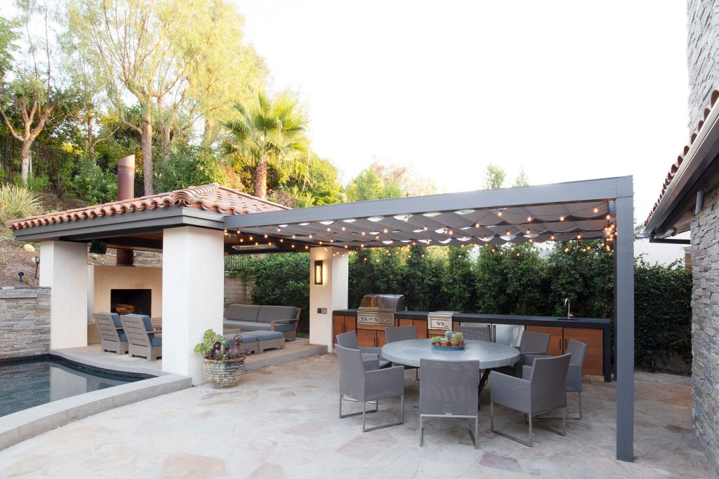 Tuscan backyard stone patio kitchen photo in Orange County with a pergola