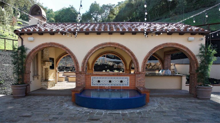 Tuscan courtyard stone patio kitchen photo in San Francisco with a gazebo