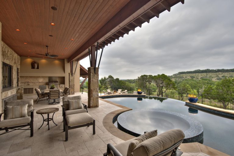 Tuscan custom home outdoor living with outdoor kitchen features an infinity edge spa and pool with fire pots.