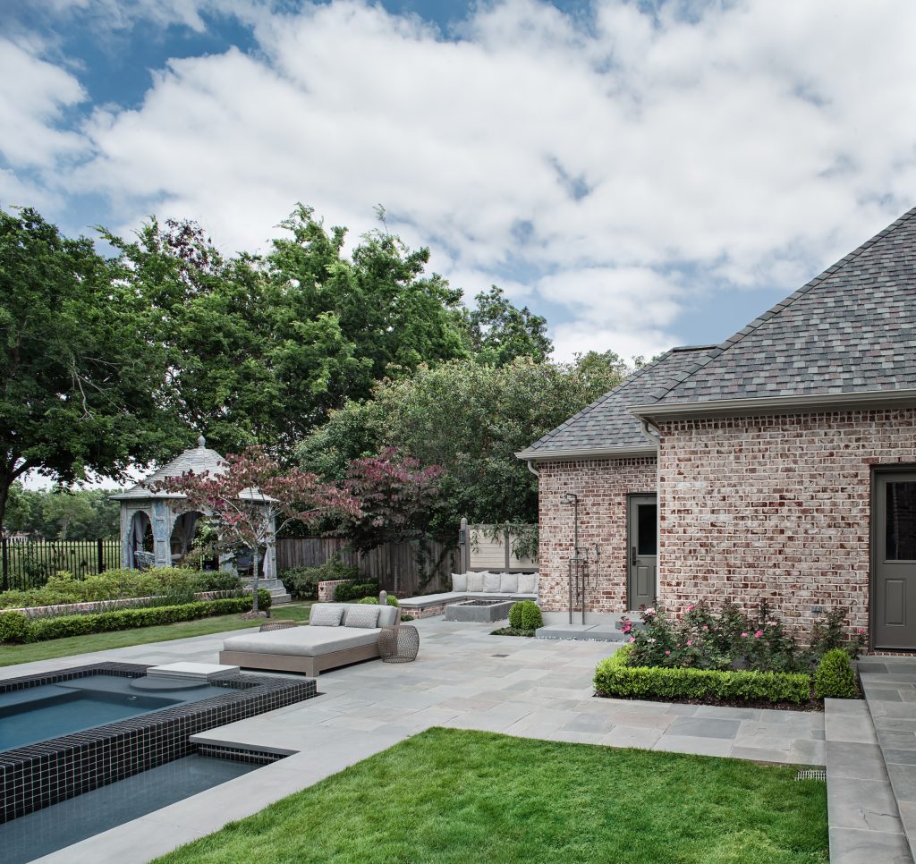 View of the east side of the garden including, terrace steps, lawn panels, bluestone paved pool deck, low brick garden wall, spa, outdoor shower, built-in fire pit, and antique teak gazebo.