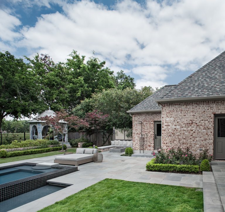 View of the east side of the garden including, terrace steps, lawn panels, bluestone paved pool deck, low brick garden wall, spa, outdoor shower, built-in fire pit, and antique teak gazebo.