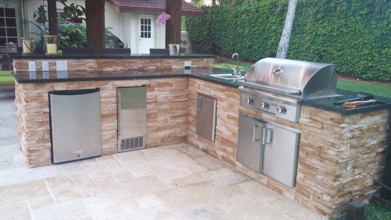 We custom designed this L shaped outdoor kitchen with raised bar, stacked stone with black granite counter top. Blaze Grill and accessories such as stainless steel storage, outdoor refrigeration and sink.