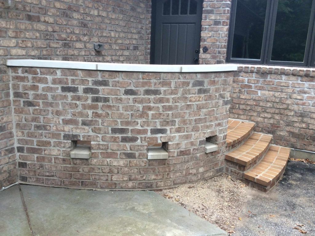 We surrounded this porch with a curved brick wall with a decorative water weep. The porch and steps were covered with a brick paver.